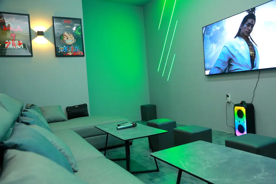 Pokój karaoke z zielonym światłem LED, sofą i telewizorem na ścianie, dom w Sajgonie