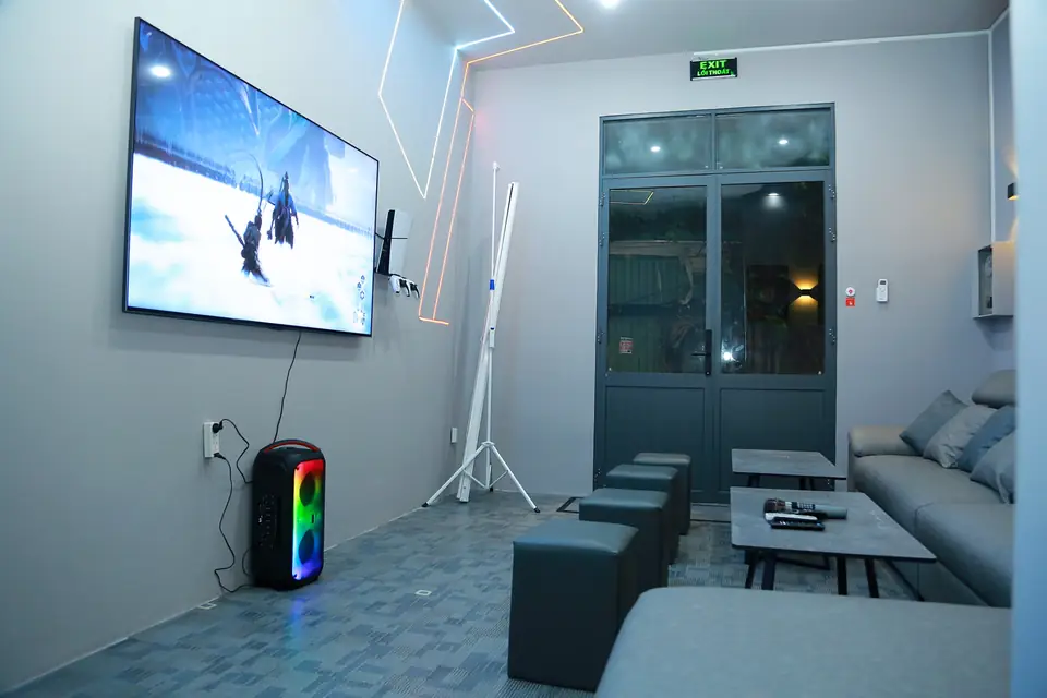 Grande TV a parete, strisce LED colorate e divano grigio