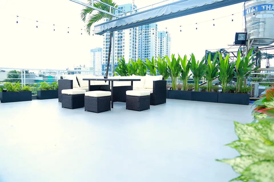 낮의 루프탑, 다크 라탄 소파와 크림색 쿠션, 긴 화단